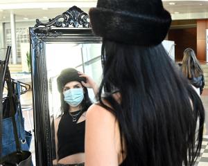 Stallholder and Otago Polytechnic student Geo Castle tries on a vintage fur hat at her stall....