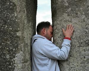 A man touches the stones during spring equinox celebrations at Stonehenge stone circle, near...