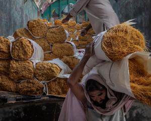Asar Khan, 43, carries bundles of wrapped vermicelli after they are unloaded from the back of a...