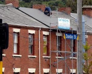 A building contractor replaces a slate tile roof with corrugated iron on one of the historic...