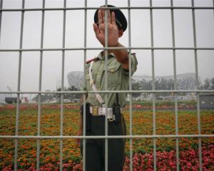 A Chinese security guard asks not to have his photo taken in front of China's National Stadium,...