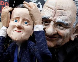 A demonstrator dressed as Rupert Murdoch holds a puppet depicting Britain's Prime Minister David...