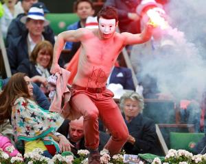 A flare-wielding Homen group protester jumps on to the court during the French Open final between...