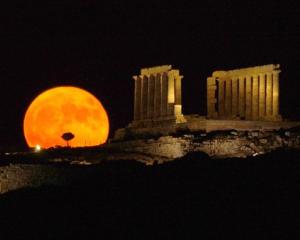 A full moon rises behind the ancient temple of Posseidon, in Sounio about 73km southeast of...