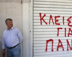 A hotel worker stands next to the shutter of a closed hotel during a protest against cutbacks and...