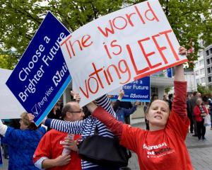 A Labour Party supporter holds her sign in front of a National Party supporter as the two groups...
