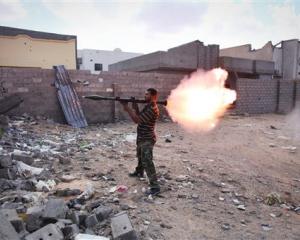 A revolutionary fighter fires a rocket-propelled grenade at Gaddafi loyalists in downtown Sirte,...