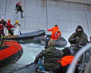 A Russian Coast guard officer is seen pointing a gun at a Greenpeace International activist as...