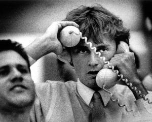 A sharemarket dealer has his hands full during hectic trading at the Auckland Stock Exchange....