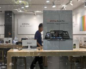 A shopkeeper dressed as an Apple store employee looks out from a window of a shop masquerading as...
