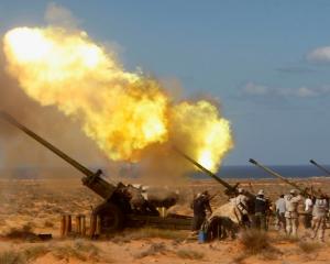 Anti-Gaddafi forces fire a Howitzer at the artillery line in Om El Khanfousa, Libya. Photo:...