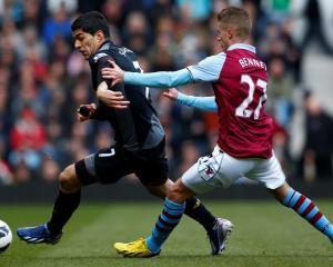 Aston Villa's Joe Bennett challenges Liverpool's Luis Suarez (L) during their English Premier...