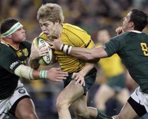 Australia's James O'Connor tries to break the tackles of South Africa's Werner Kruger, left, and...