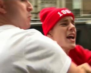 Canadian pop star Justin Bieber is held back by a member of his security team as he confronts a...
