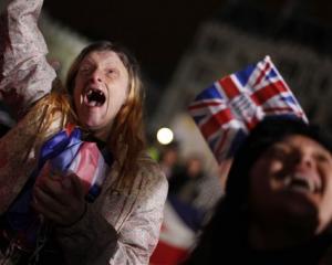 Caryll Foster, of Kingston on Thames, England, left, cheers with other royal enthusiasts as they...