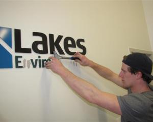 Connor Harrison, of Sign It Signs, removes Lakes Environmental signs from the authority's office...