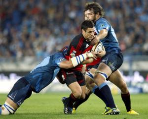 Crusaders first-five Daniel Carter, center, is tackled by Bulls captain Victor Matfield, left,...