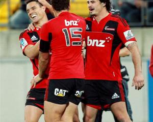 Dan Carter, Israel Dagg and Zac Guildford of the Crusaders celebrate Carter's try. (Photo by...