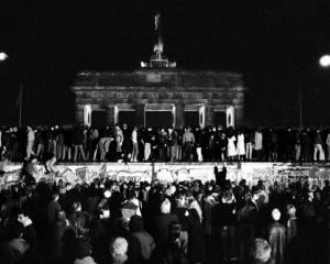 East and West German citizens celebrate as they climb the Berlin wall at the Brandenburg gate...