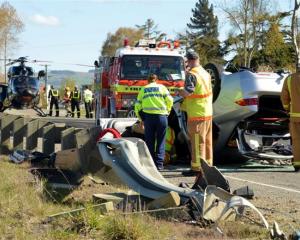 Emergency services inspect a car that overturned on State Highway 1, near Waikouaiti, yesterday....