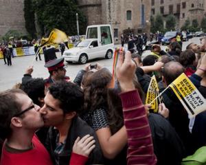 Gay activists kiss during a protest as Pope Benedit XVI passes by on his popemobile on his way to...