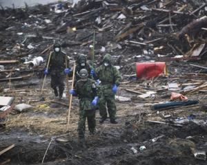 Ground Self-Defence Force members search in the rain for victims' belongings in a devastated area...