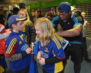 Highlanders winger Waisake Naholo signs an autograph for Lily Genge (10) as her brother Xavier...