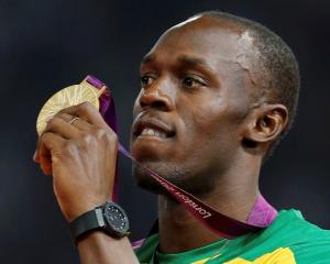 Jamaica's Usain Bolt displays his gold medal during the presentation ceremony for the men's 200m...