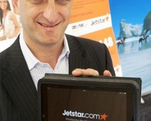 Jetstar Group chief executive Bruce Buchanan holds one of the Apple iPads the airline will offer...