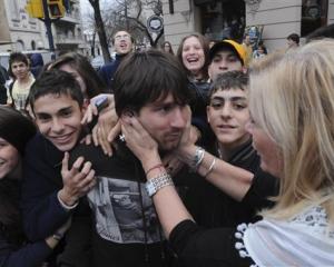 Lionel Messi, centre, is grasped by an unidentified woman as he leaves a restaurant in Rosario,...