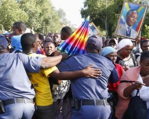 Mourners try to break through a police barrier attempt to view the body of former South African...