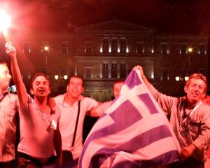 New Democracy supporters hold flares as they celebrate in front of the parliament in central...