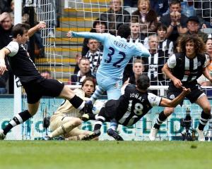 Newcastle United players tackle Manchester City's Carlos Tevez (C) as he tries to score during...