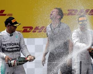 Nico Rosberg (R) and Lewis Hamilton splash each other with champagne after the Austrian Grand...