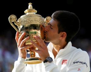 Novak Djokovic kisses the trophy after beating Roger Federer in their men's singles final at...