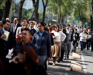 Office workers gather on Paseo de la Reforma avenue in Mexico City after being evacuated from the...