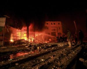 Palestinians gather as firefighters try to control a fire after an Israeli airstrike in the Rafah...