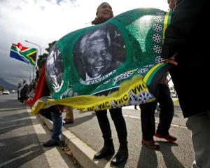 People hold a banner bearing the face of former South African president Nelson Mandela as they...