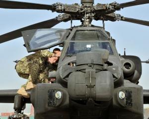 Prince Harry climbs up to examine the cockpit of an Apache helicopter at Camp Bastion in...