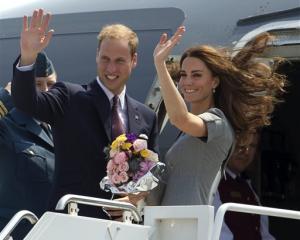 Prince William and Kate, the Duke and Duchess of Cambridge, wave as they board their plane as...