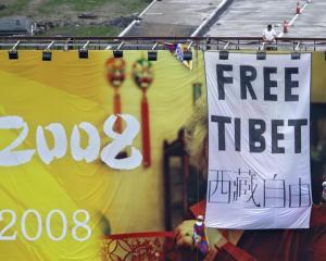 Pro Tibet activists unfurl a "Free Tibet" banner and Tibetan flags on top of a Beijing Olympics...