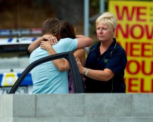Relatives of a man who was attacked and killed by a shark at Muriwai Beach yesterday hug while...