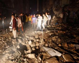Residents and rescue workers gather at the site of a bomb blast in a residential area in Karachi....