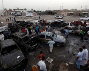 Residents gather at the site of a car bomb attack in Baghdad's Sadr City. REUTERS/Thaier al-Sudani