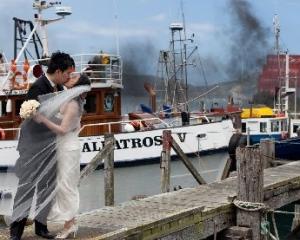 Rob Ong kisses his bride May Eng on Careys Bay wharf on Monday afternoon, just as a large fire...