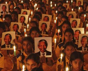Schoolchildren hold candles and portraits of Nelson Mandela during a prayer ceremony at a school...