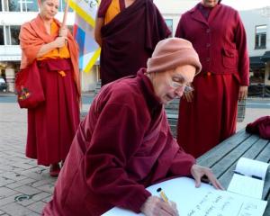 Sonam Chokyi writes a translation of a message of protest from Geshe Jampa Tenzin (back, centre)...
