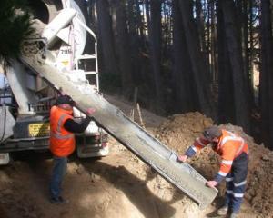 SouthRoads crew Ian Schroeder (left) and Daryl Falconer pour concrete into a hole in Ridge Rd,...