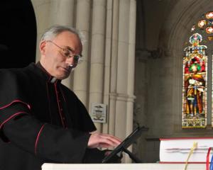 St Joseph's Cathedral priest Monsignor John Harrison accesses material on an iPad lying next to...