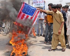 Supporters of Pakistan's Muslim League burn a representation of the US flag during a...